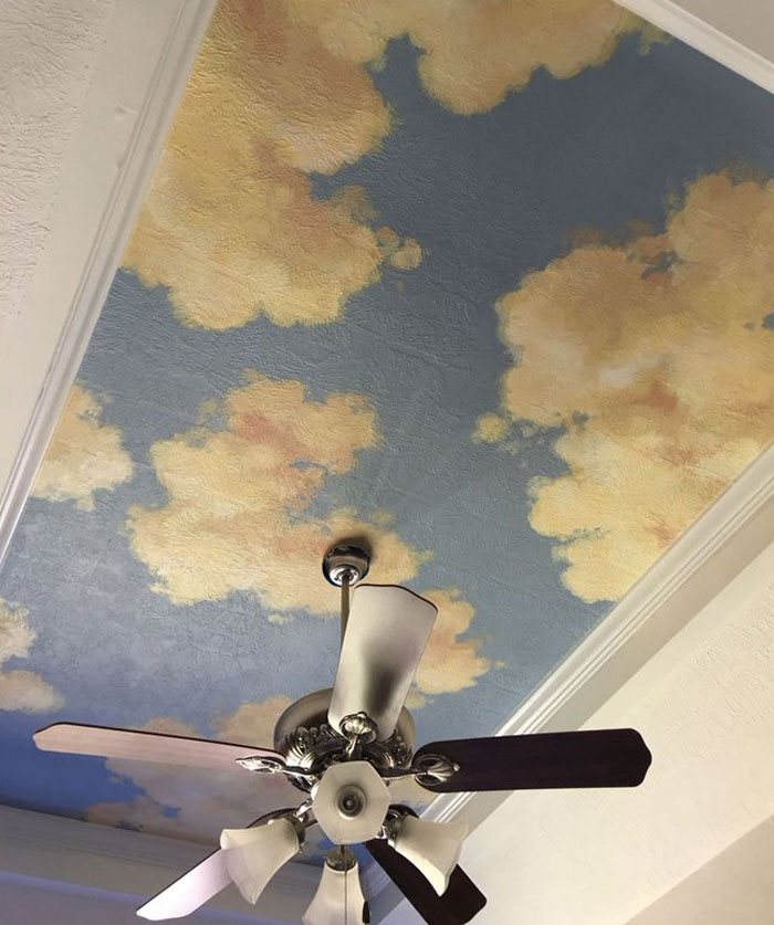 Ceiling with cloud mural and ceiling fan showcasing cool interior design ideas for transforming home spaces.