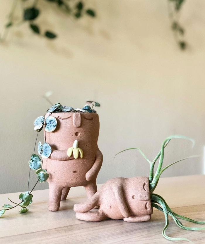 Two unique plant pots with face designs displaying cool interior design ideas for stylish home decor on a wooden surface.
