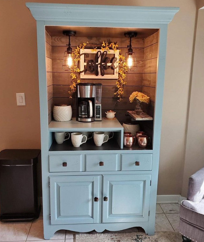 Cozy coffee station inside a blue cabinet with warm lighting, mugs, and decorative accents showcasing cool interior design ideas.