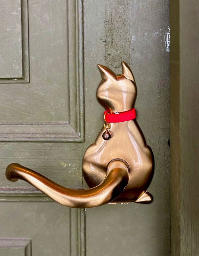Bronze cat-shaped door handle with a red collar, showcasing a cool interior design idea for home decor.