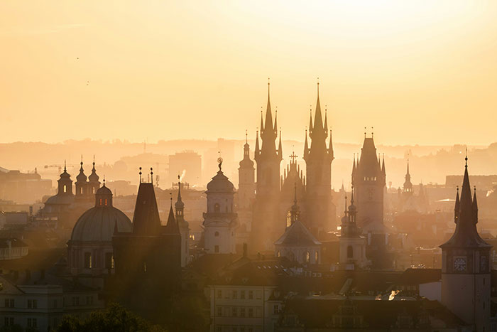 Golden sunset over a historic European skyline with gothic spires, travel scene referencing Tokyo