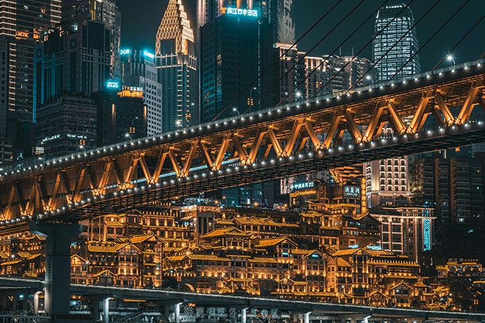 Tokyo night cityscape with lit suspension bridge and glowing riverside buildings, dense urban skyline