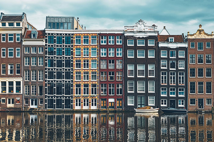 Colorful canal-front narrow houses reflected in water with small boats, historic European cityscape, Tokyo