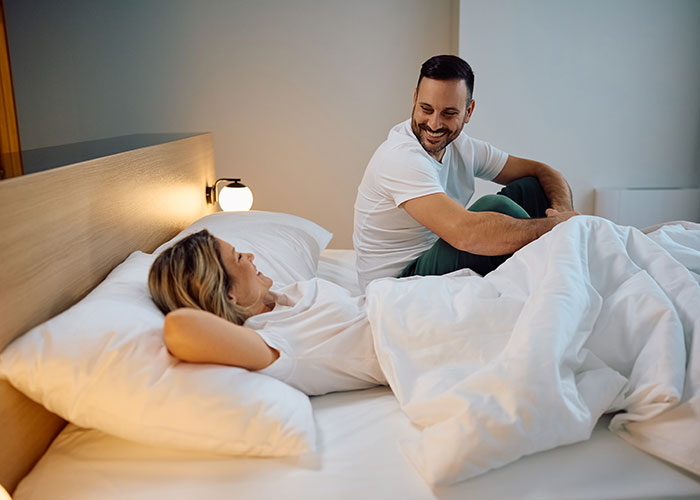 Couple sharing dumb house rules laughing and relaxing together in bed during a cozy morning at home.