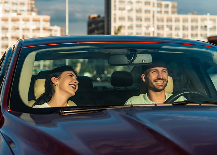 Couple smiling and enjoying a car ride together, illustrating dumb house rules couples now take seriously.