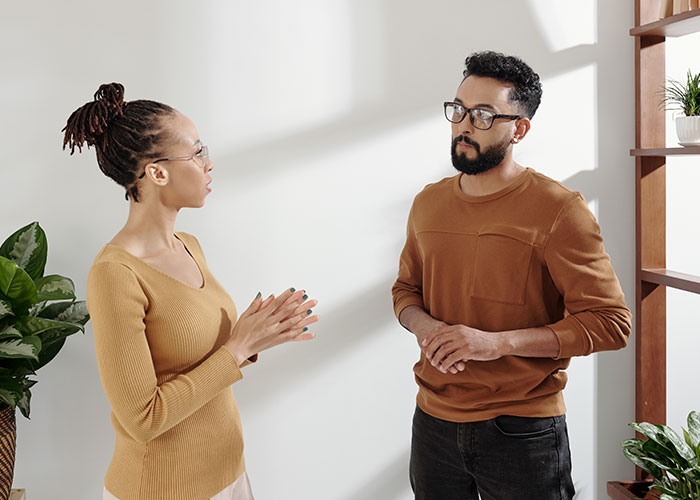 Couple having a serious conversation indoors, reflecting on dumb house rules they set up as a joke but now follow closely.