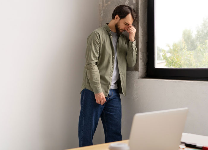 Man looking distressed by a window in a modern room, representing shock from married lady returning to a second hubby scenario.