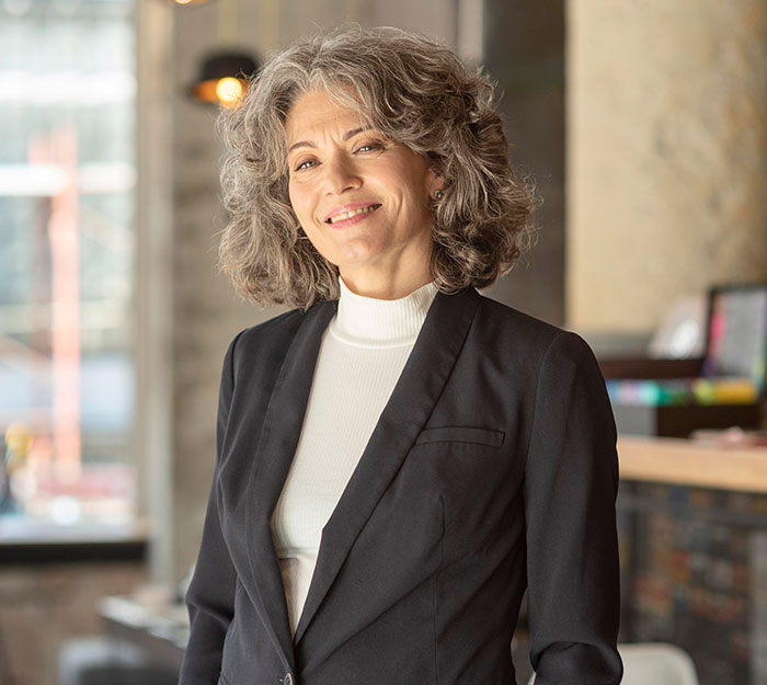 Confident mature woman smiling indoors, representing sharp intelligence that made me feel like my brain was spaghetti.