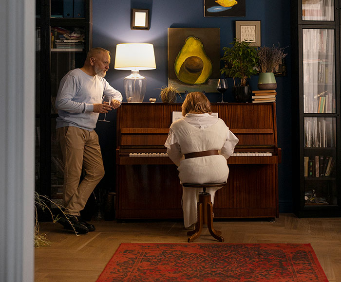 Two people in a cozy room with piano, highlighting sharp intelligence in a relaxed, creative atmosphere.