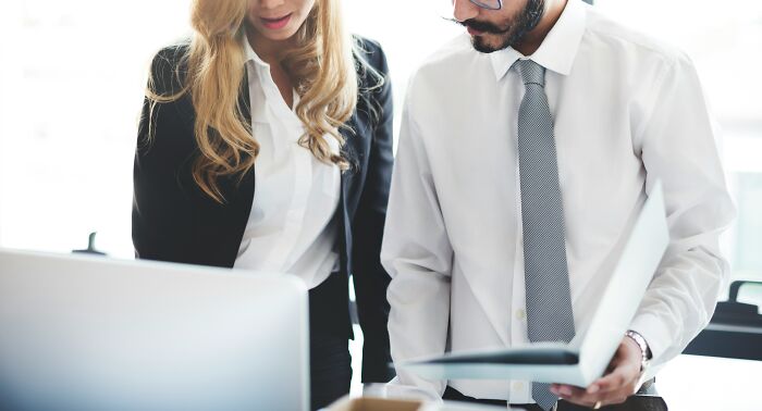 Two coworkers in professional attire reviewing documents together, illustrating worst coworkers causing work stress.