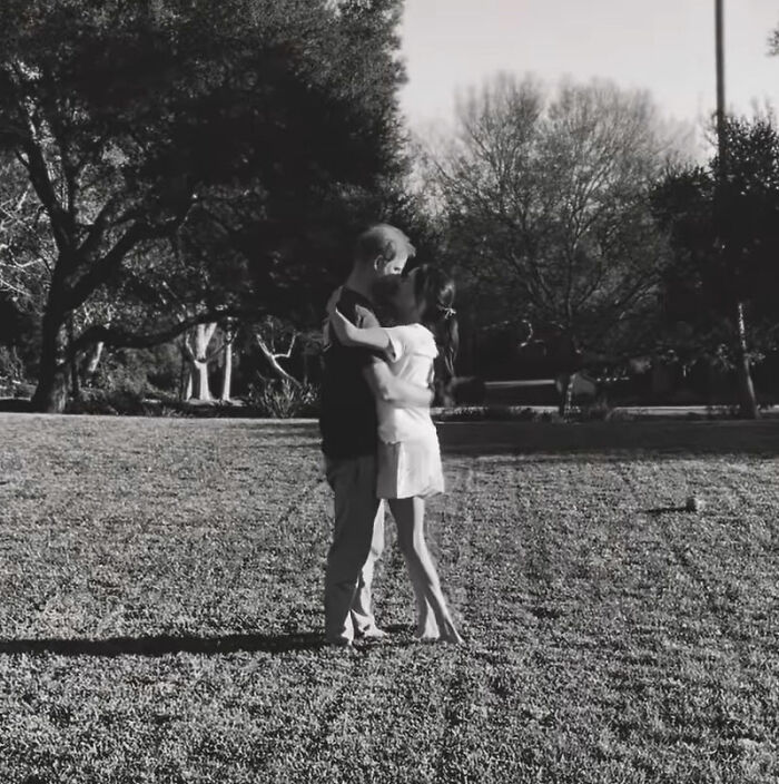 Couple embracing in a park setting in a black and white photo related to Meghan Markle's 2016 throwback post controversy.