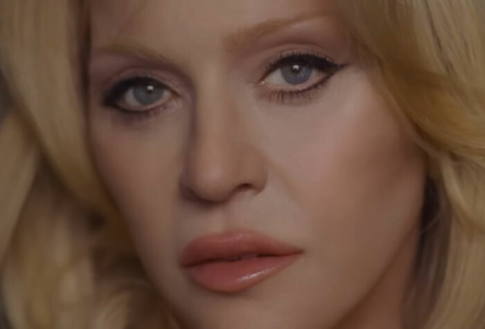 Close-up of Madonna in a raunchy Dolce & Gabbana ad featuring younger men and a controversial c****h shot.