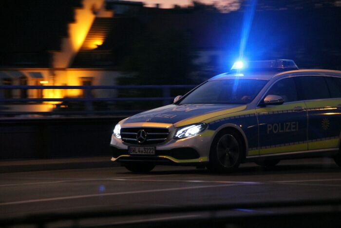 Police car with flashing lights driving at night, representing high school controversies involving law enforcement incidents.