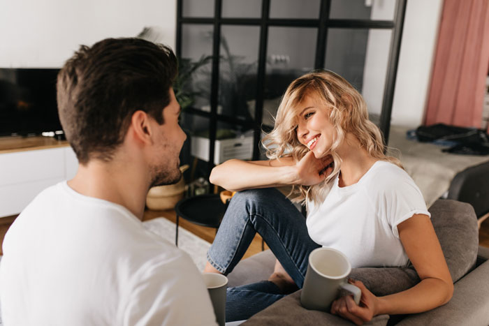 Recovering alcoholic woman on a second date, sitting on a couch with a man, looking surprised and hesitant. Recovering alcoholic woman on a second date, sitting on a couch with a man, looking surprised and hesitant.