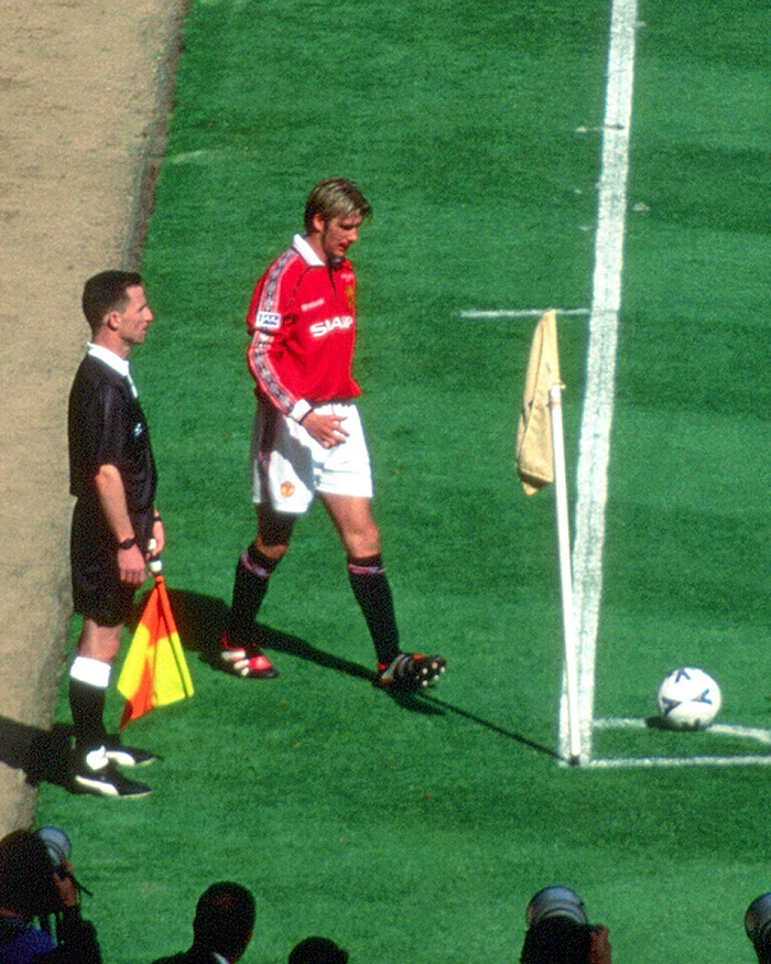 David Beckham on the soccer field near the corner flag during a match, illustrating moments in his sports career.