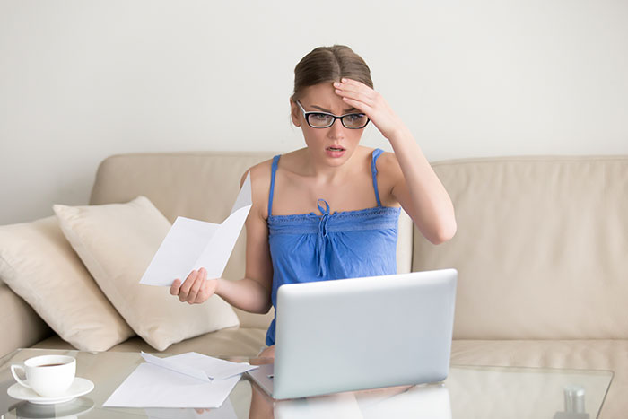 Worried stay-at-home mom reviewing bills on laptop, facing financial problems and pressure to get a job