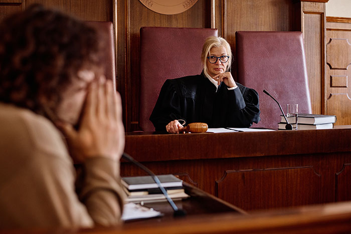 Female judge in courtroom overseeing a stressed woman during a divorce case involving financial problems and a SAHM wife.