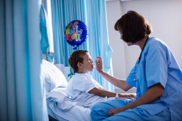 Medical professional examining young patient in hospital room with get well soon balloon, depicting healthcare and anti-vaxxer context.