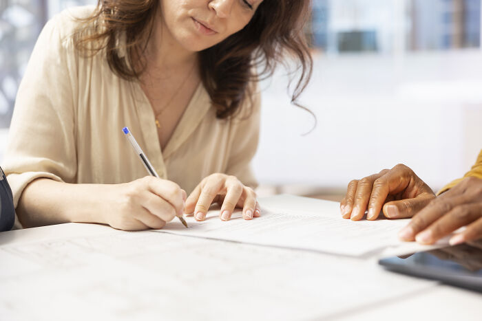 Medical professionals engaging with a patient while discussing documents in a clinical or office setting.