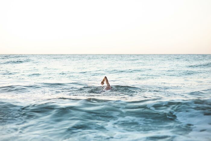 A medical professional swimming alone in open water, symbolizing challenges faced with anti-vaxxer encounters.