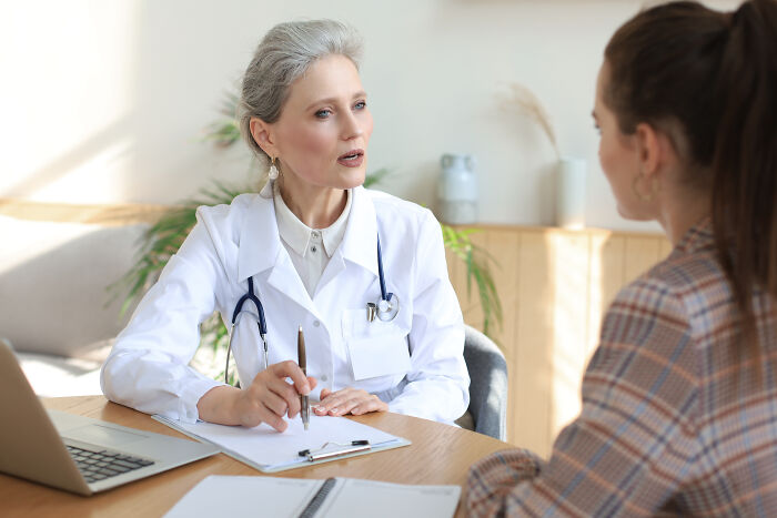Medical professional in white coat discussing vaccine concerns with a patient in a bright office setting.