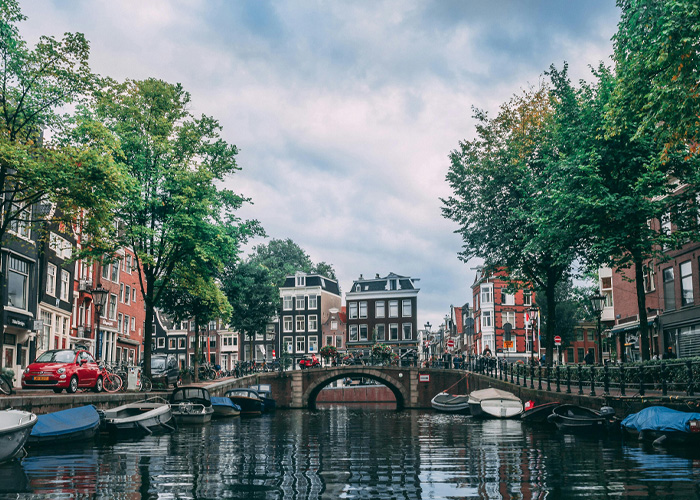 Canal scene in Dutch city with traditional buildings and boats, illustrating Dutch worker giving American boss reality check.