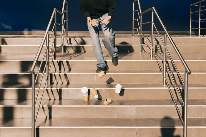 Person accidentally dropping coffee cups while walking down stairs, capturing a ridiculous moment mistaken for pranks.