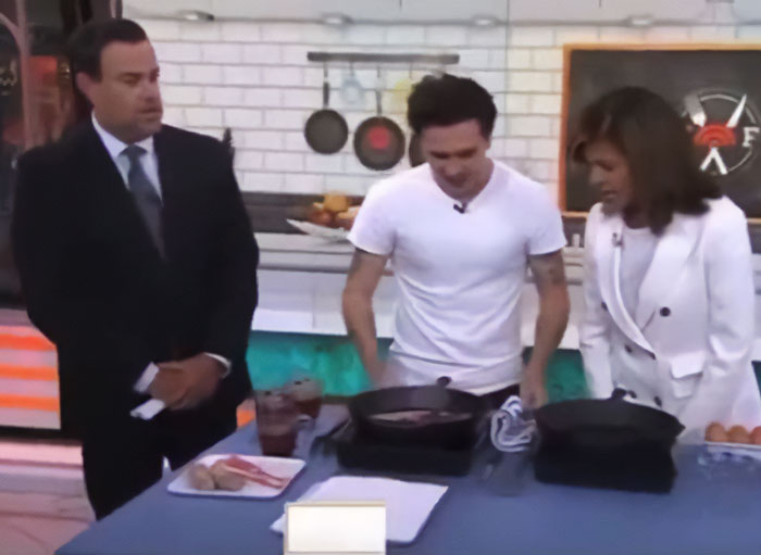 Brooklyn Beckham cooking breakfast in a kitchen studio setting, surrounded by two hosts during a live segment. Brooklyn Beckham cooking breakfast in a kitchen studio setting, surrounded by two hosts during a live segment.