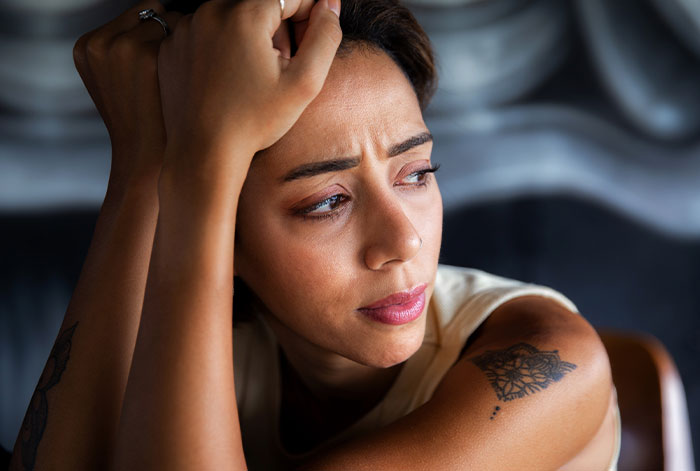 Woman looking distressed indoors, struggling with emotions related to ex&rsquo;s dog and shelter threats.