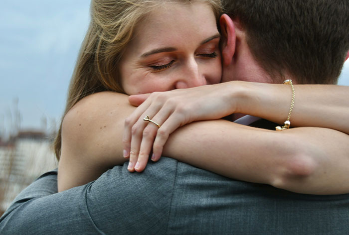 Woman embracing man tightly, showing engagement ring, symbolizing discovery of first cousin engagement after family Christmas. Woman embracing man tightly, showing engagement ring, symbolizing discovery of first cousin engagement after family Christmas.
