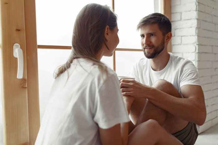 Couple having a serious conversation at home about prenup disagreements leading to canceled engagement.