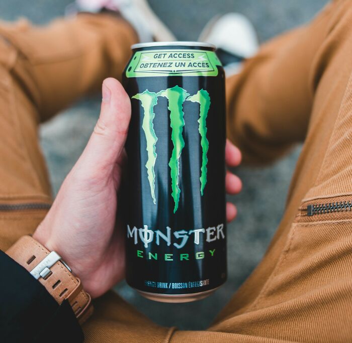 Hand holding a Monster Energy drink can illustrating bizarre office rules that make people say are you kidding me.