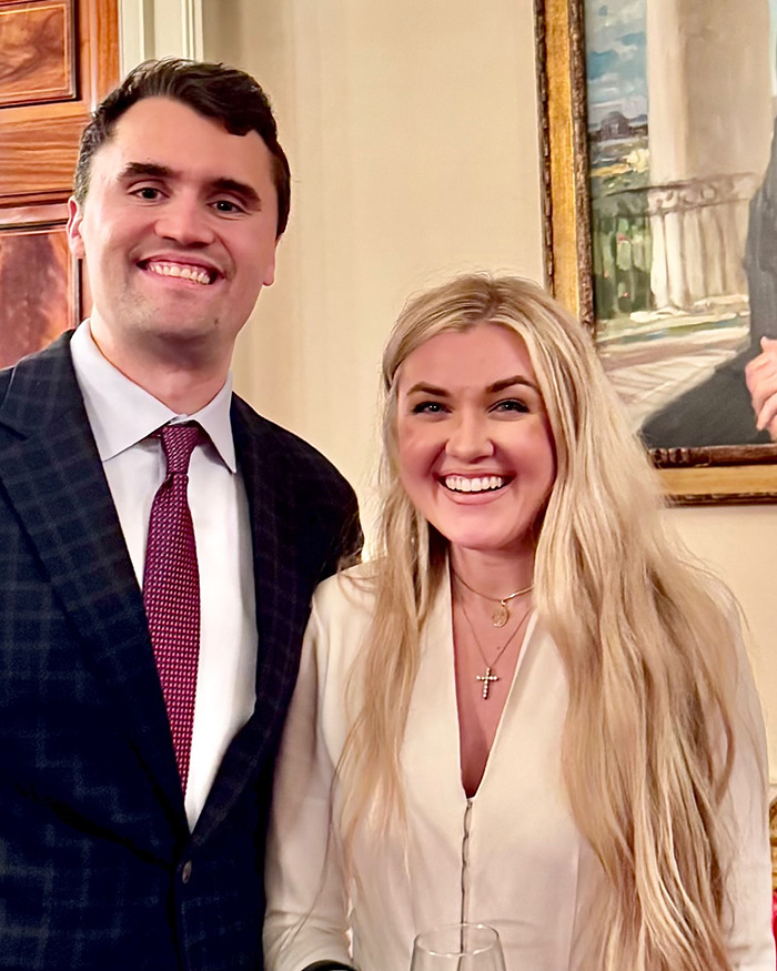 Erika Kirk smiling with a man indoors, showing her makeup transformation before Charlie's assassination. Erika Kirk smiling with a man indoors, showing her makeup transformation before Charlie's assassination.