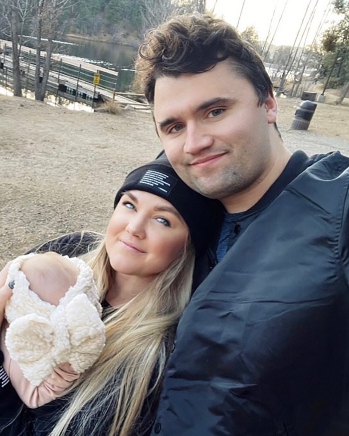 Erika Kirk outdoors with a man and baby, showing a natural makeup look before Charlie's assassination. Erika Kirk outdoors with a man and baby, showing a natural makeup look before Charlie's assassination.