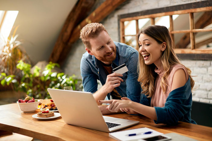 Young couple sharing a joyful moment while using a laptop, highlighting ex-house drama relationship tension.