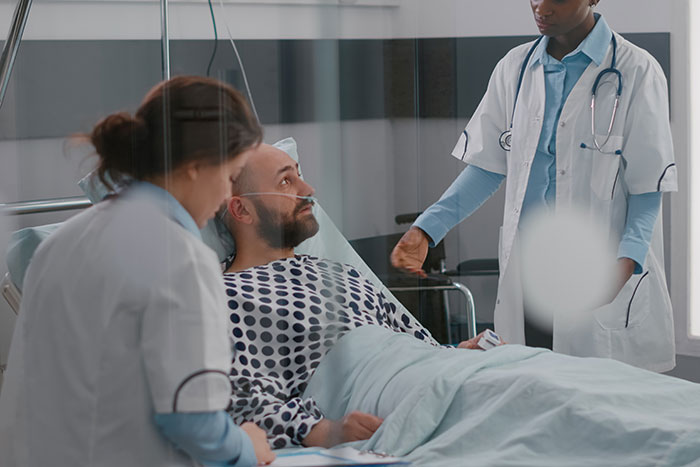 Man in hospital bed being examined by two medical professionals, illustrating moments when the so called expert was wrong.