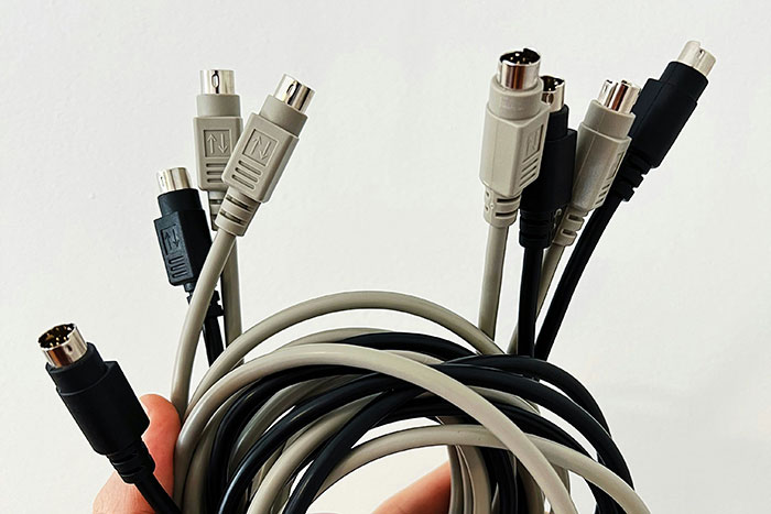 Hand holding tangled black and gray cables with multiple connectors, illustrating expert confusion and being wrong.