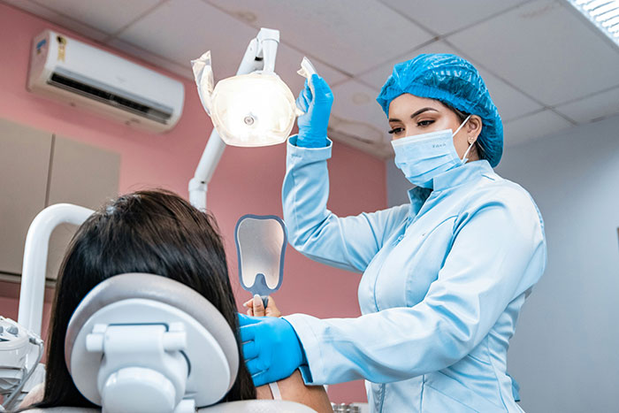 Dentist in protective gear examining patient in dental clinic, illustrating moments when so called expert was wrong.