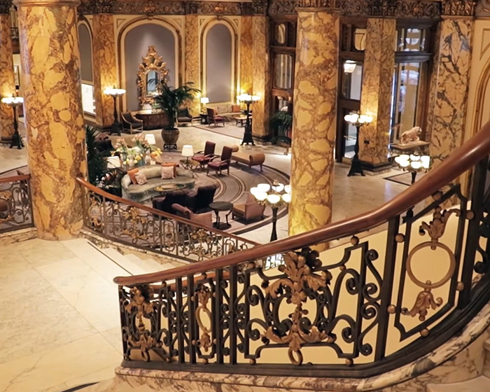 Luxurious interior of a grand historic building with marble columns and ornate wrought iron staircase railing. Luxurious interior of a grand historic building with marble columns and ornate wrought iron staircase railing.
