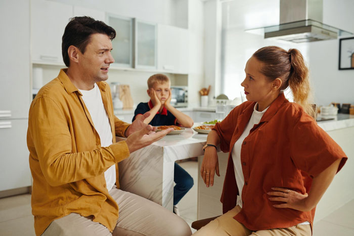 Man and woman arguing in kitchen while child looks upset, highlighting mom snapping over aunties' favoritism toward one kid