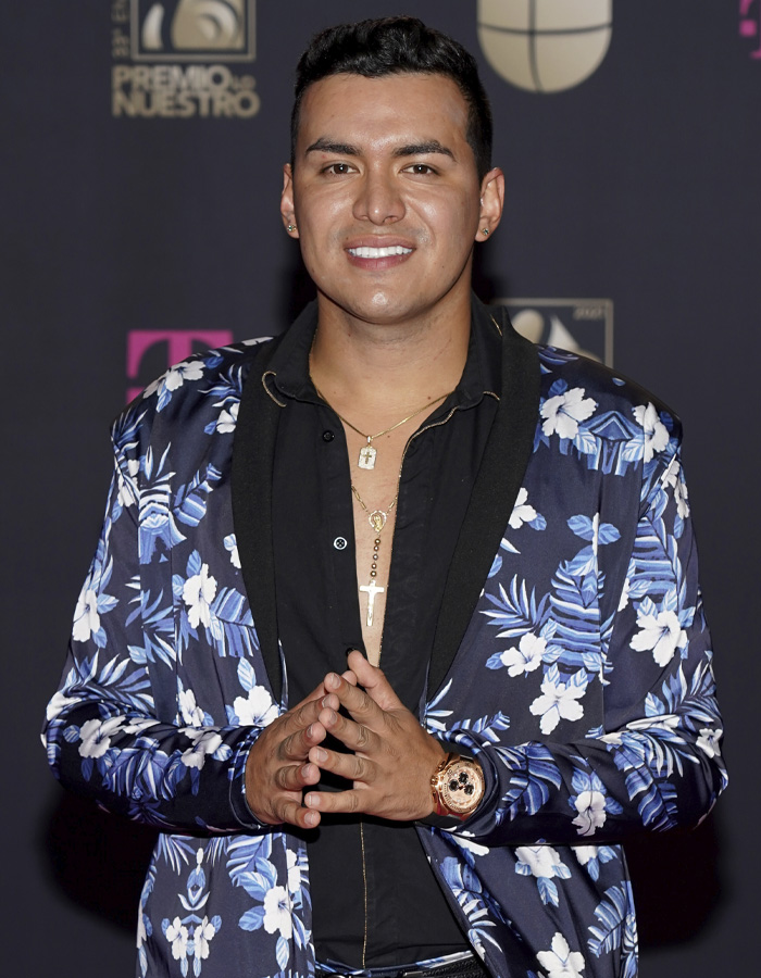 Famous singer wearing floral suit and gold accessories posing at an award event before tragic plane crash. Famous singer wearing floral suit and gold accessories posing at an award event before tragic plane crash.