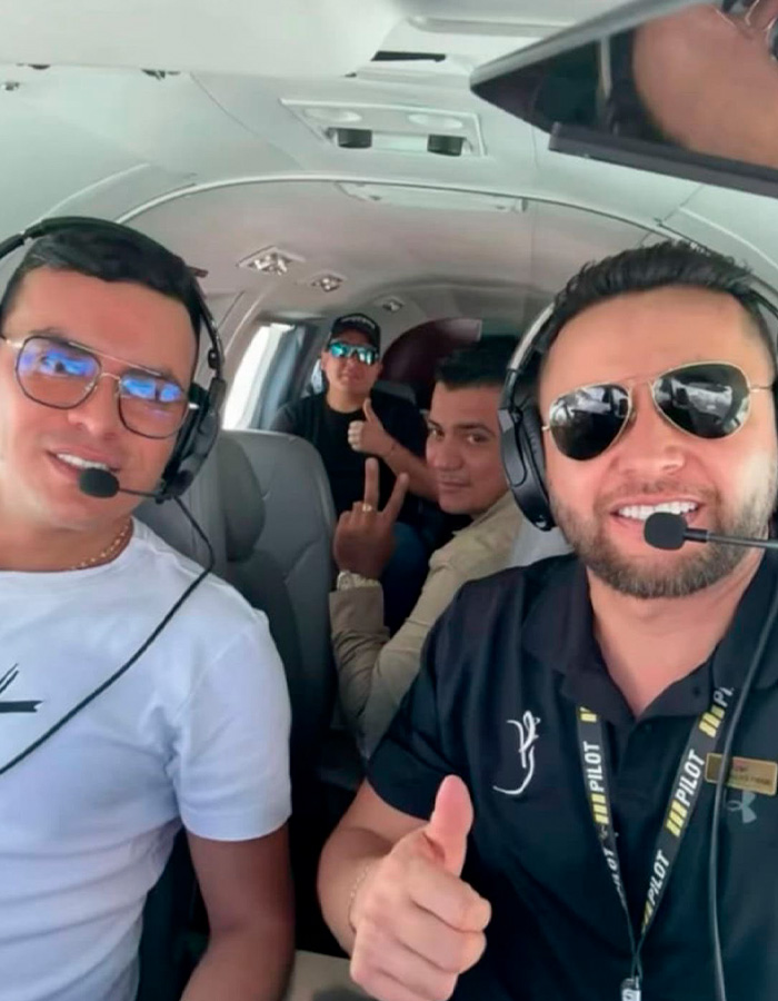 Four men inside a small plane wearing pilot headsets, two giving thumbs up, relating to famous singer plane crash.