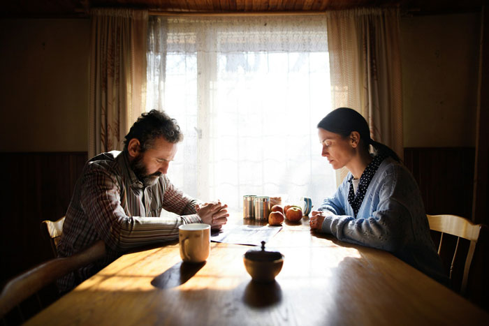Man and woman sitting silently at a kitchen table, reflecting on family struggles and children viewed as failures by their dad.
