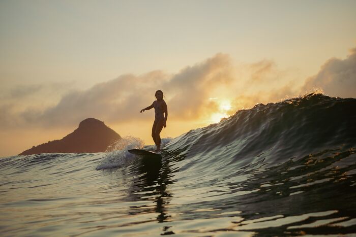 Surfer balancing on a wave at sunset, highlighting unexpected daily dangers you might not realize you’re exposed to.