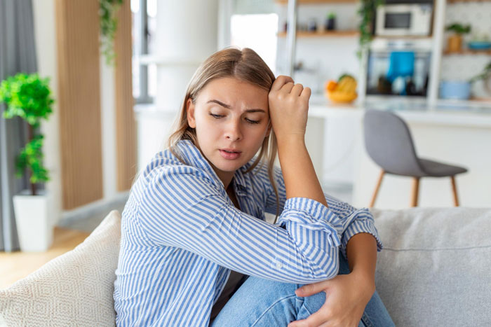 Young woman sitting on a couch looking distressed, reflecting on a difficult relationship boundary turning into therapy battles.