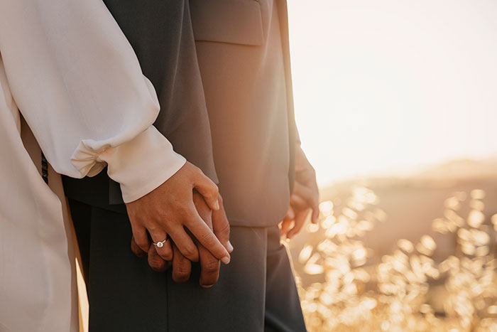 Couple holding hands with engagement ring at sunset, emotional scene suggesting breaks off engagement Couple holding hands with engagement ring at sunset, emotional scene suggesting breaks off engagement