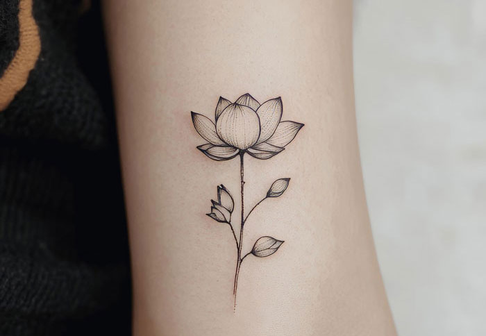 Minimalist black lotus flower tattoo on forearm, highlighting fianc&eacute;&rsquo;s tattoo designed by ex in a relationship conflict.