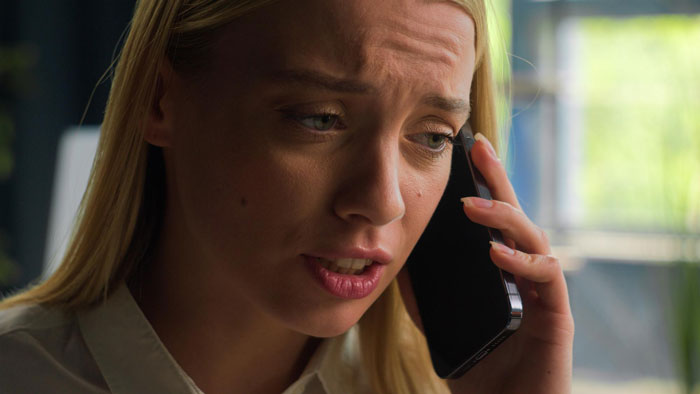 Woman looking worried while speaking on phone, reflecting tension over fianc&eacute;&rsquo;s tattoo designed by ex and wedding postponement.