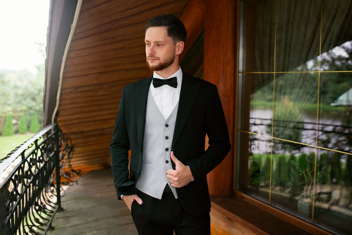 Groom in wedding suit standing on porch, thoughtful about fiance and handling money matters before ceremony. Groom in wedding suit standing on porch, thoughtful about fiance and handling money matters before ceremony.