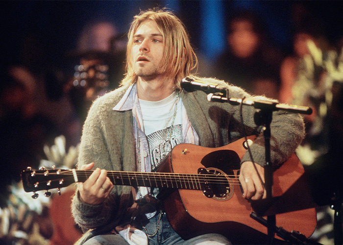 Kurt Cobain playing acoustic guitar during a live performance, highlighting evidence about his passing and forensics.